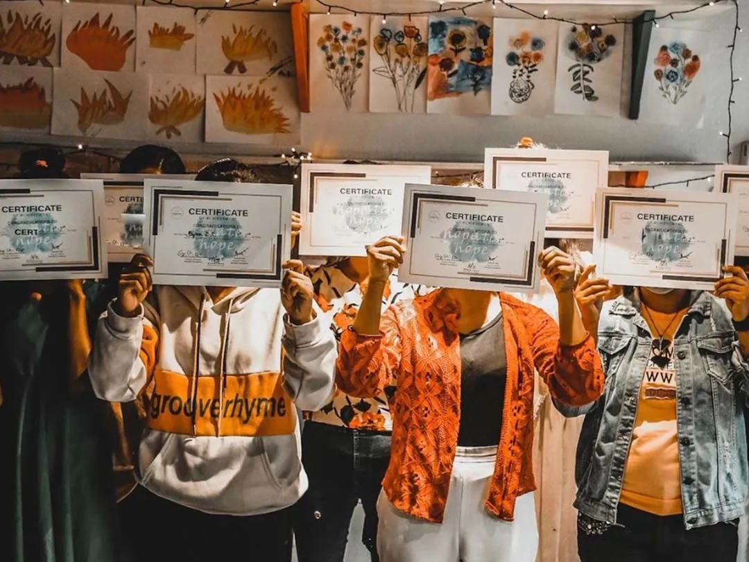 children holding up a certification in front of their faces