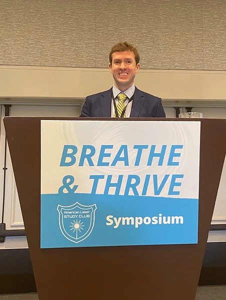Dr Baxter standing at the Breath & Thrive Sumposium podium