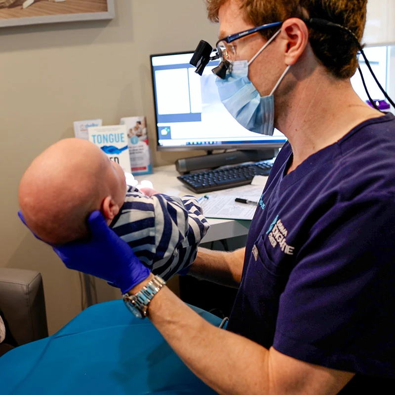 Dr Baxter holding a baby after a tongue tie procedure